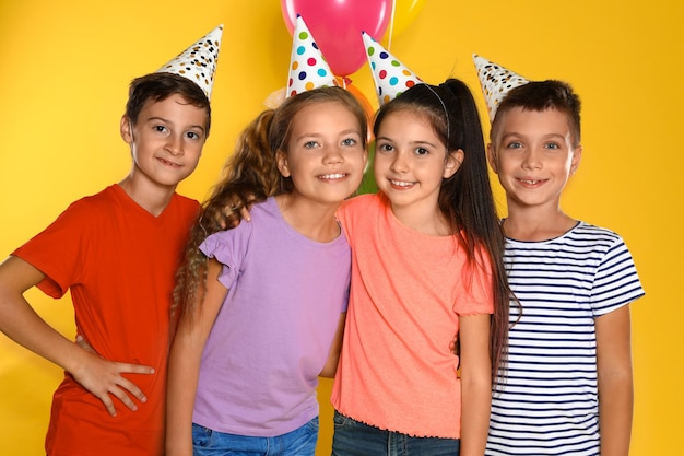 Niños felices en sombreros de fiesta sobre fondo amarillo Celebración de cumpleaños