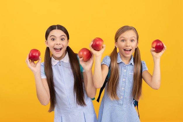 Niños felices sostienen manzanas para una merienda saludable de regreso a la escuela alimentación escolar de fondo amarillo