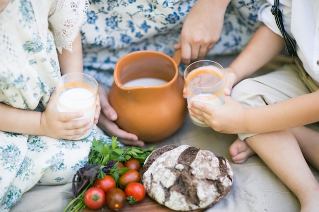 Los niños felices tienen pan y leche en sus manos comen verduras en la naturaleza comida sana en el pueblo