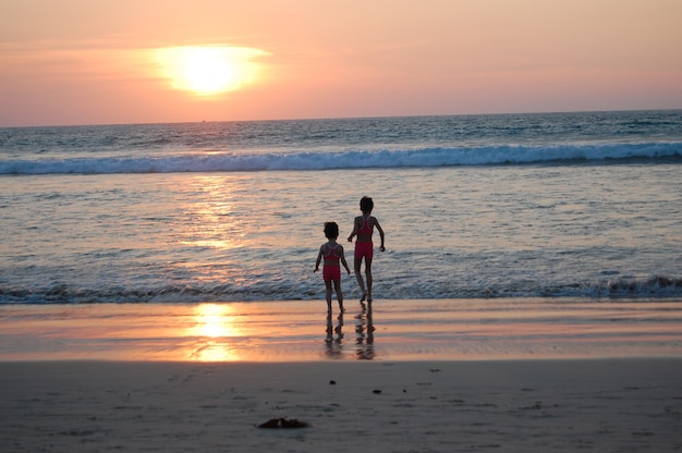 Niños felices en vacaciones en la playa. Niñas corriendo cerca del mar