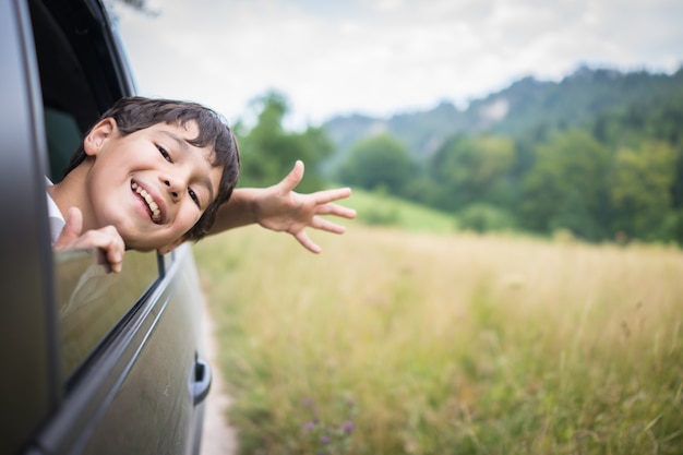 Los niños felices viajan en el coche