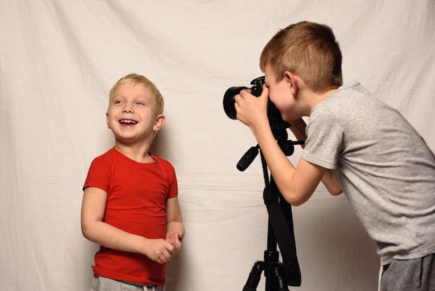 Los niños se fotografían entre sí con una cámara réflex. Estudio en casa. Joven blogger Blanco
