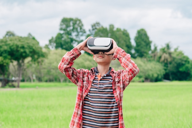 Niños con gafas de video de realidad virtual y alegres en el hermoso fondo de la naturaleza