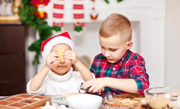 Niños con gorro de Papá Noel para hornear galletas de Navidad en casa