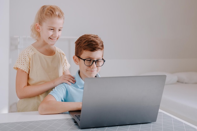 Niños guapos felices frente a la computadora portátil Concepto de educación en línea Tarea de computadora