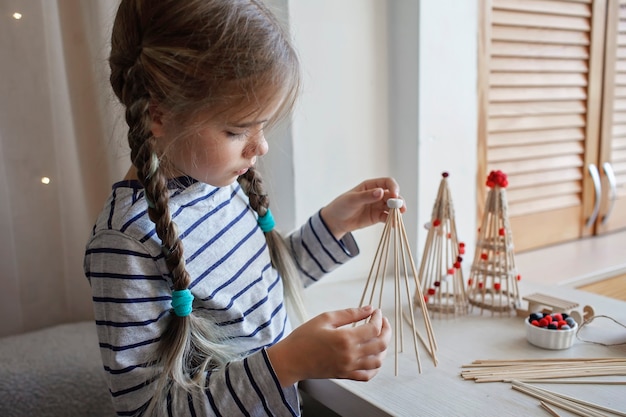 Los niños hacen un árbol de navidad hecho a mano con palos de bambú adorno reutilizable diy decoración de año nuevo