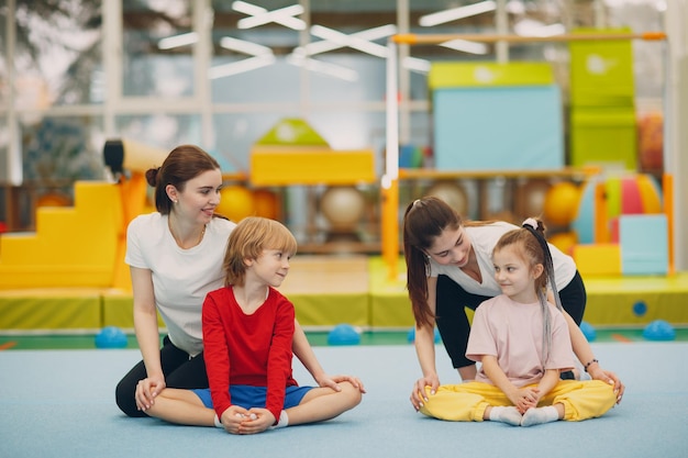 Niños haciendo ejercicios de estiramiento en el gimnasio en el jardín de infantes o la escuela primaria concepto de deporte y fitness para niños