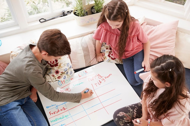 Niños haciendo una lista de tareas en la pizarra en casa