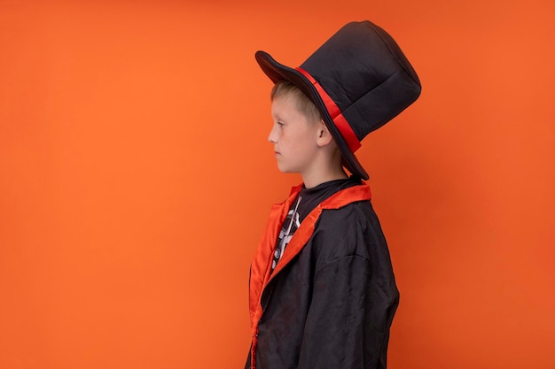 Niños de Halloween Un niño con un disfraz de esqueleto sostiene un gato o linterna Fondo naranja Copia espacio Un niño con un sombrero de abrigo negro sostiene una calabaza de Halloween Lugar para el texto