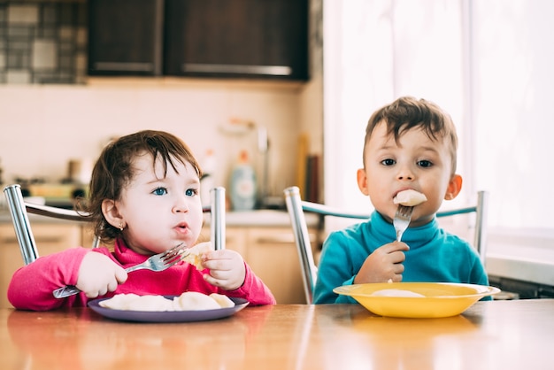 Los niños, hermano y hermana comen bolas de masa muy lindas y divertidas lindas