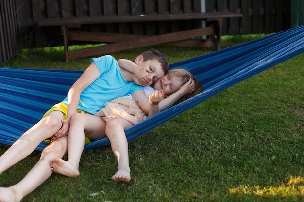 Niños hermano y hermana descansando en el jardín en una hamaca