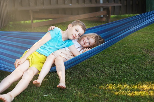 Niños hermano y hermana descansando en el jardín en una hamaca