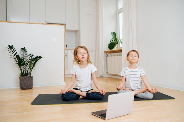 Niños hermanos haciendo yoga juntos meditando con los ojos cerrados