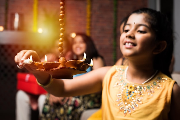 Los niños indios celebrando Diwali, Deepawali, Bhai Dooj o Rakhi o Raksha Bandhan con flor rangoli, regalos, diya