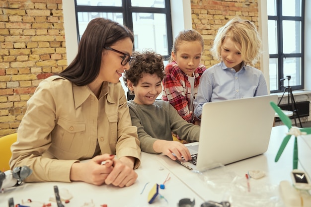 Los niños inteligentes de alfabetización digital aprenden a programar usando un portátil sentado a la mesa en un aula