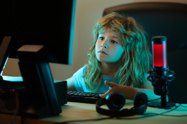 Niños inteligentes aprendiendo en línea en casa niño caucásico trabajando en una computadora portátil en una habitación oscura en la escuela nocturna