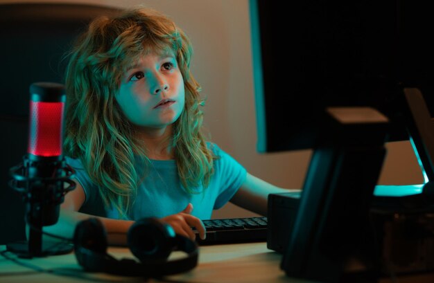 Niños inteligentes aprendiendo en línea en casa Niño caucásico trabajando en una computadora portátil en una habitación oscura por la noche Concepto de aprendizaje en línea de estudio escolar Colegial escribiendo en el teclado