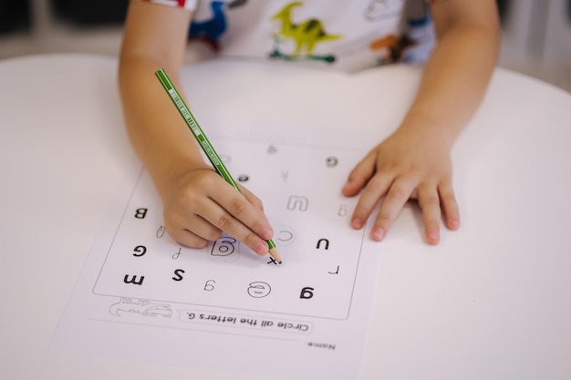 Los niños en el jardín de infantes circulan diferentes letras con un lápiz.