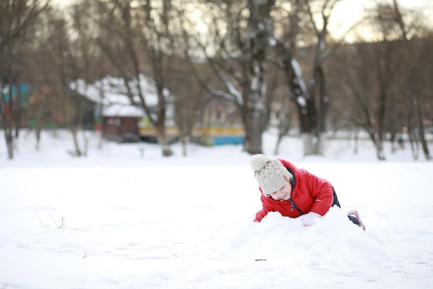Los niños juegan afuera en el invierno. Juegos de nieve en la calle.