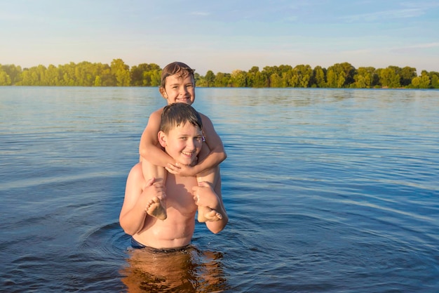 Los niños juegan en el agua y miran a la cámara en un día soleado infancia feliz