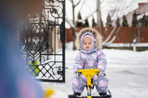 Los niños juegan al aire libre en la nieve Dos hermanitas disfrutan de un paseo en trineo