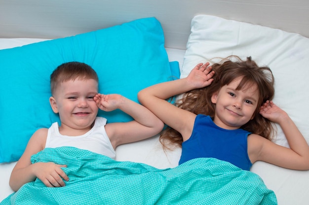 Los niños juegan en la cama. Primer plano de niños felices jugando en casa en la cama. El concepto de fin de semana de vacaciones en familia.