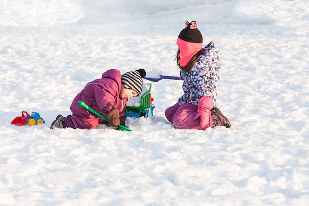 Los niños juegan con carros y palas. Concepto de limpieza de nieve de la ciudad