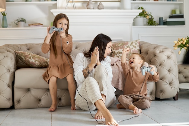 Los niños juegan en la consola con su madre.