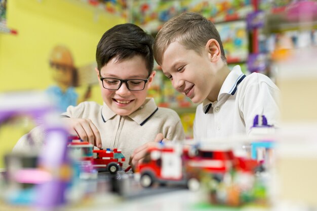 Los niños juegan en el diseñador en la mesa. Dos niños juegan juntos con bloques de plástico de colores en el centro de juegos de la escuela.