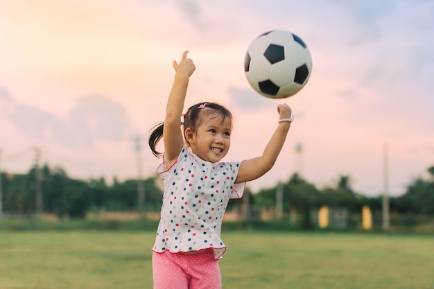 Los niños juegan fútbol soccer para hacer ejercicio bajo la luz del sol.