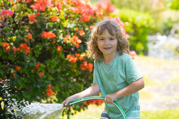 Los niños juegan con manguera de jardín de agua en el patio al aire libre niños diversión de verano niño pequeño jugando con agua h