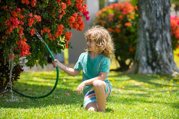 Los niños juegan con manguera de jardín de agua en el patio Diversión de verano para niños al aire libre Niño pequeño jugando con agua h