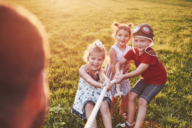 Los niños juegan con papá en el parque. Tiran de la cuerda y se divierten tendidos en un día soleado