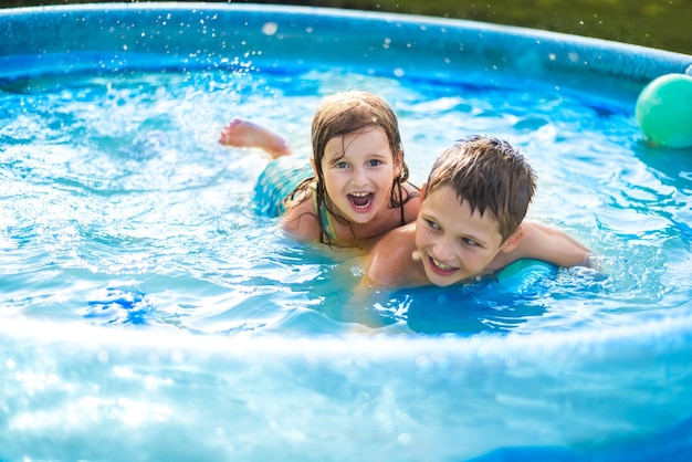 Los niños juegan con una pelota en la piscina en verano. niña y niño . linda niña en la piscina al aire libre