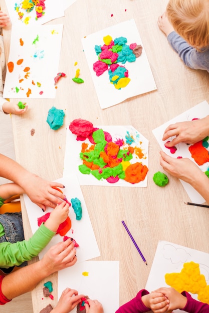 Los niños juegan con plastilina en la mesa.