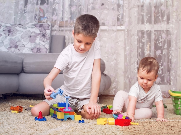 Los niños juegan en el suelo en el diseñador Hermano y hermana pasan tiempo juntos