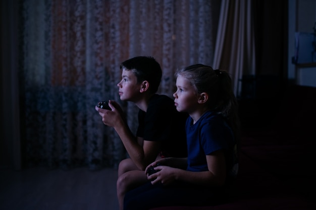 Los niños juegan videojuegos cuarto oscuro