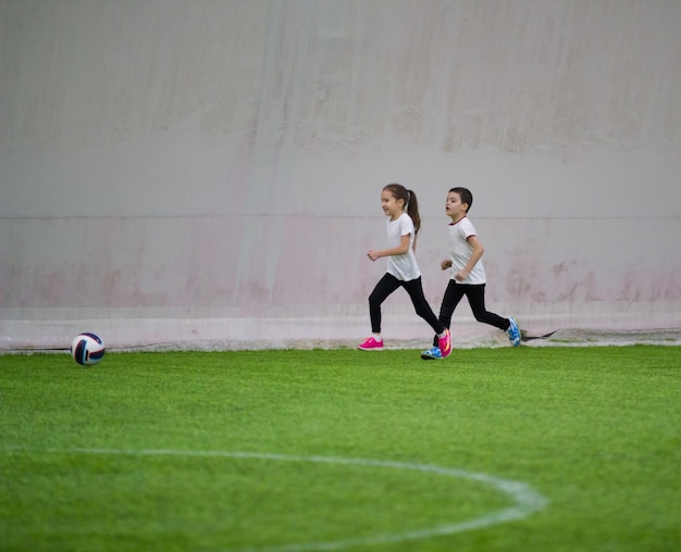 Niños jugando al fútbol en el interior una niña y un niño jugando