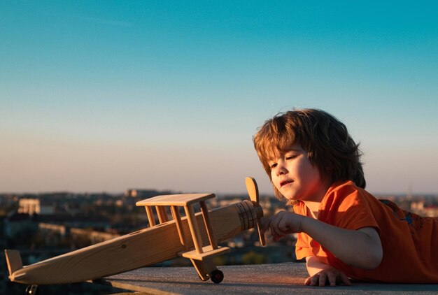 Niños jugando con un avión de madera vintage al aire libre retrato de niños contra el fondo del cielo de verano