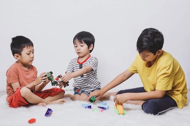 Niños jugando con bloques de juguete sobre fondo blanco.