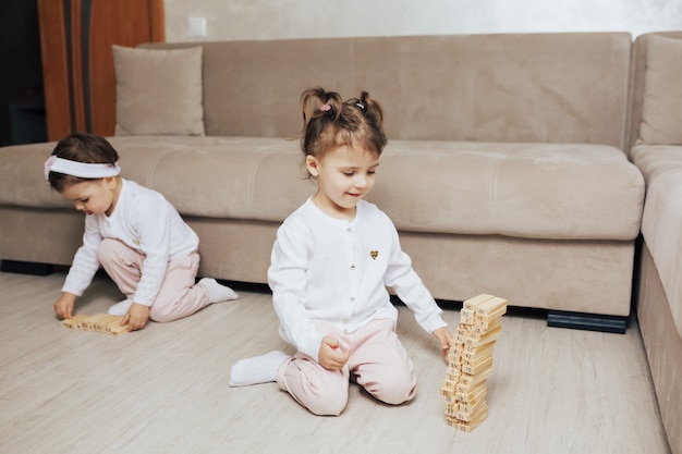 Niños jugando con bloques de madera en casa en la sala de estar.