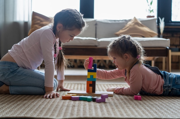 Niños jugando con bloques de madera en el suelo de su habitación.