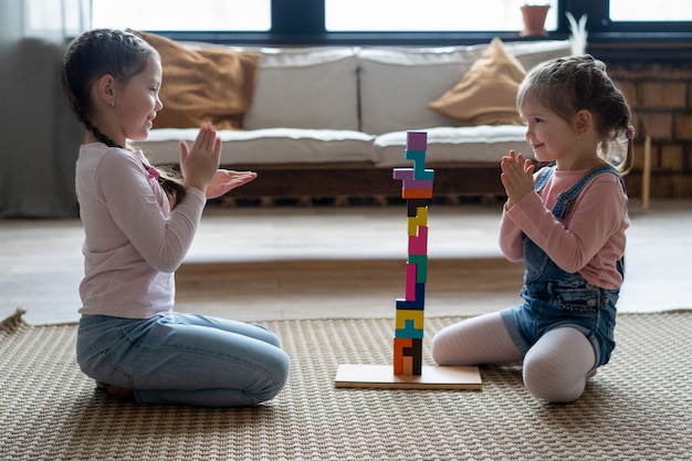 Niños jugando con bloques de madera en el suelo de su habitación.