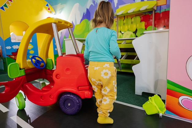 Niños jugando en el centro de juegos interior patio niña en coche de juguete