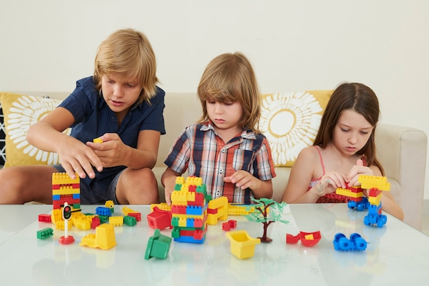 Foto niños jugando con coloridos ladrillos de juguete juntos en la mesa en la luminosa sala de juegos