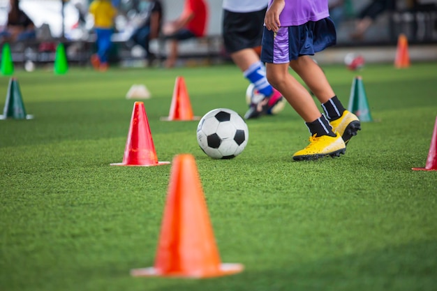 Niños jugando cono de tácticas de balón de fútbol de control en campo de hierba con antecedentes de formación Formación de niños en fútbol