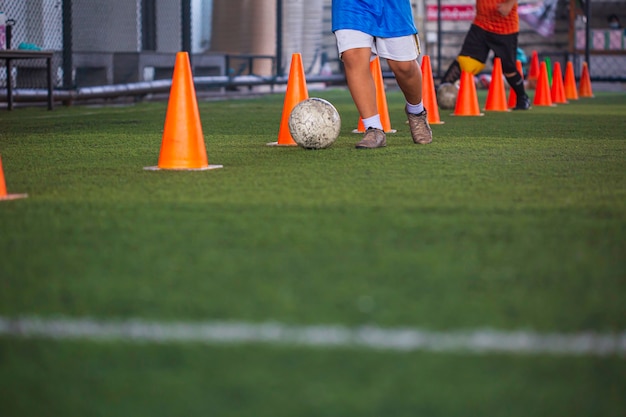 Niños jugando cono de tácticas de balón de fútbol de control en campo de hierba con antecedentes de formación Formación de niños en fútbol