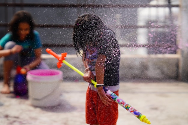 Niños jugando holi con agua y colores y disfrutando.