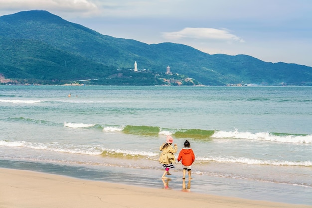 Niños jugando a lo largo de la playa de China en Danang en Vietnam. También se la llama Playa Non Nuoc. Mar de China Meridional y Montañas de Mármol en el fondo.