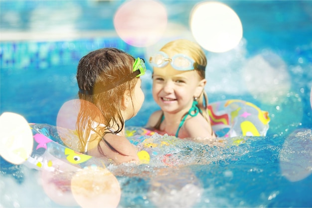 Niños jugando en la piscina. Dos niñas divirtiéndose en la piscina.